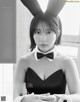 A woman in a black dress with bunny ears on her head.