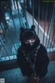 A person wearing a mask and goggles standing in front of a railing.