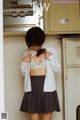 A woman in a white shirt and plaid skirt standing in front of lockers.