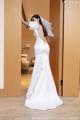 A woman in a white wedding dress standing in front of a door.