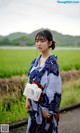 A woman in a blue and white kimono standing in the rain.